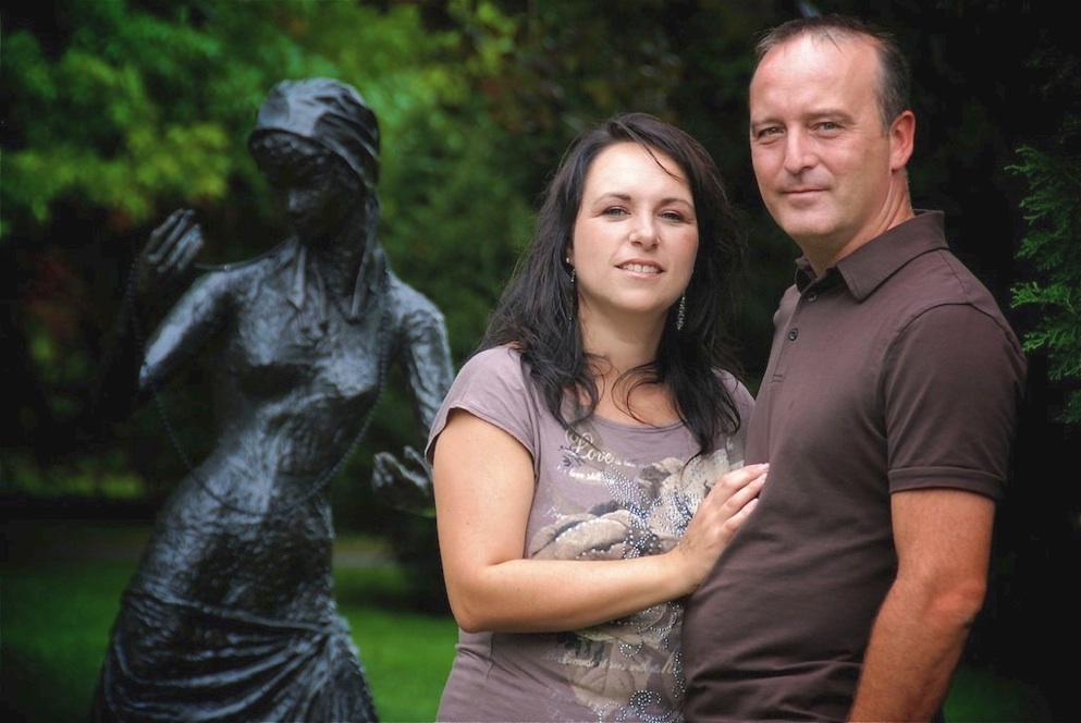 couple devant la statue de bronze jeune femme au collier
